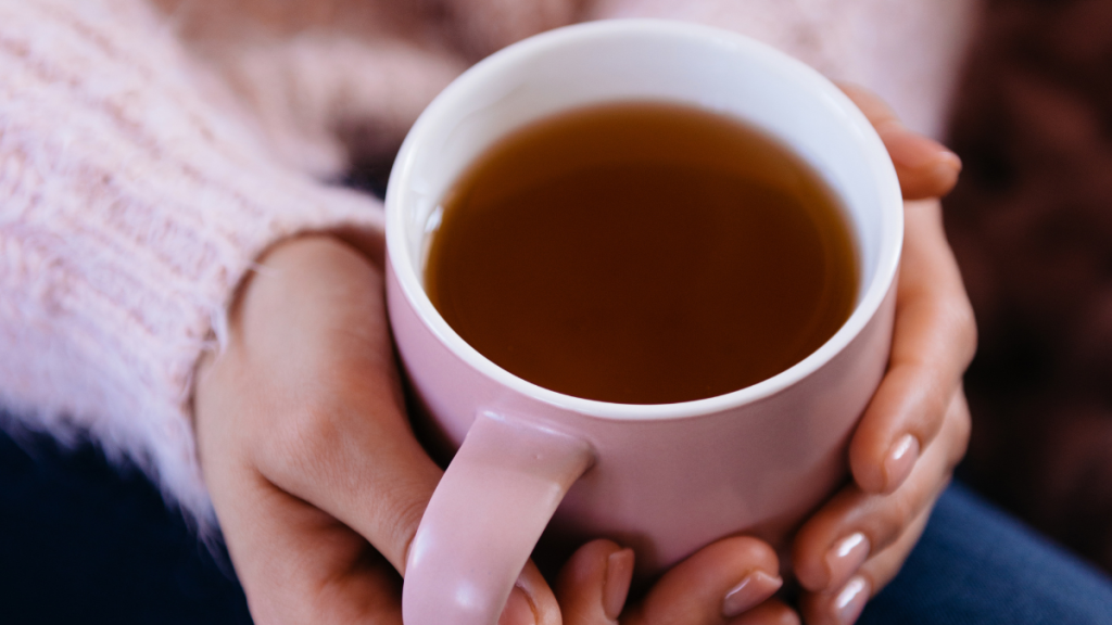Frauenhände umschließen eine warme Teetasse als Symbol für Entspannung bei PMS, Zyklus-Migräne und Histaminunverträglichkeit.