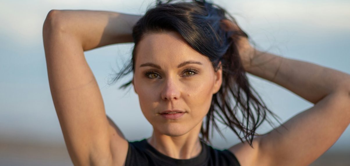 Sportliche Frau nach ihrem Workout mit den Armen über dem Kopf