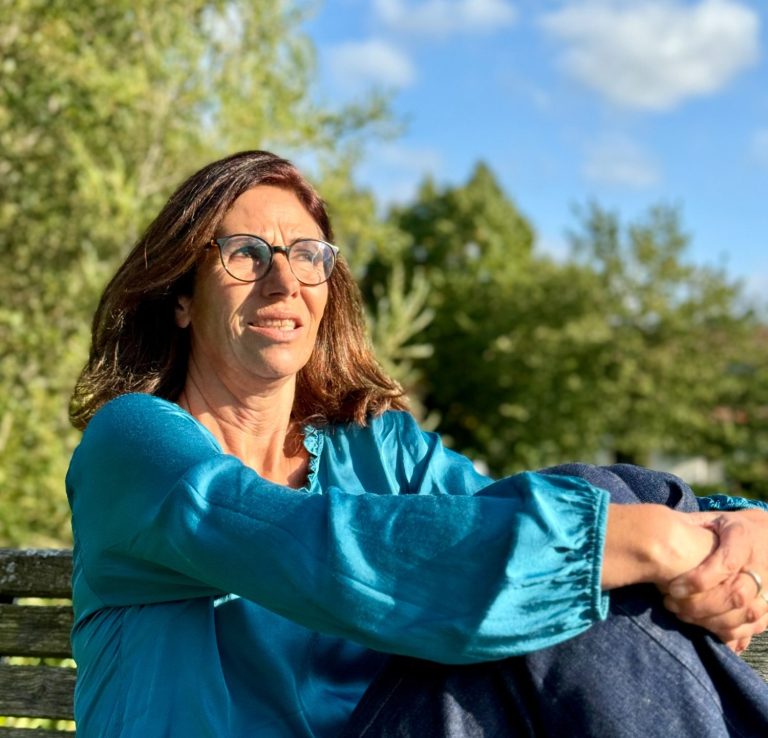 Heike Votteler entspannt in der Sonne auf einer Parkbank in Oy-Mittelberg