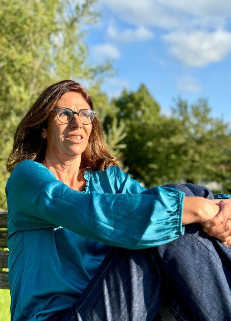 Heike Votteler entspannt in der Sonne auf einer Parkbank in Oy-Mittelberg
