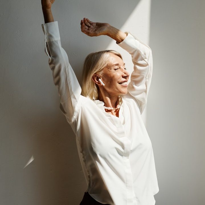 Tanzende Frau mittleren Alters in weißer Bluse 