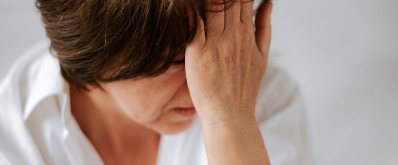 Eine gestresste Frau hält sich die Hand vor das Gesicht