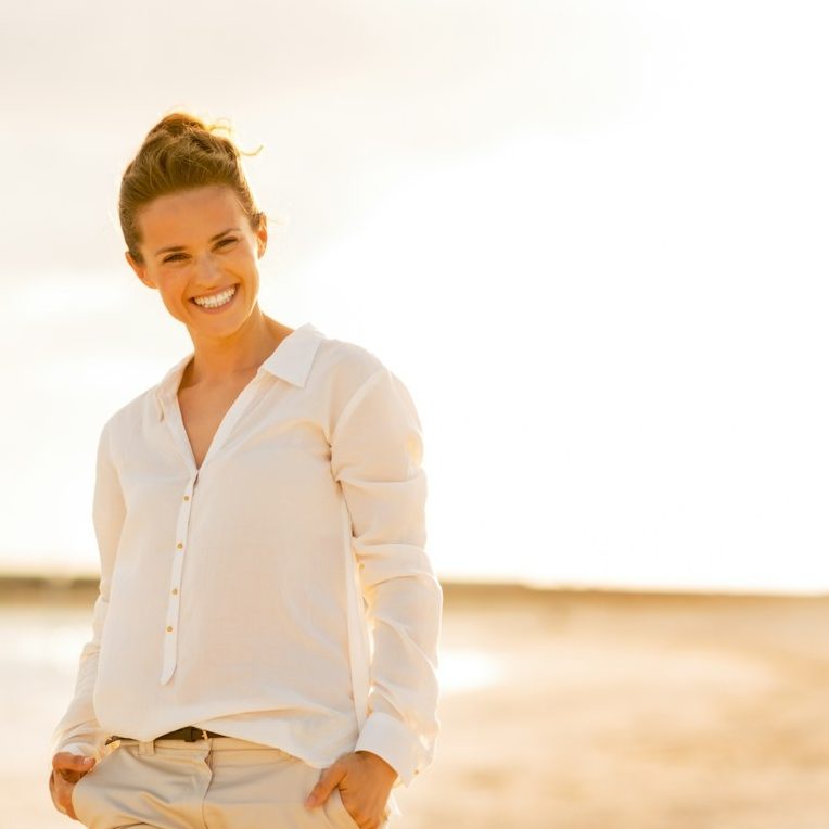 Entspannte, lächelnde Frau mit heller Bluse in der Natur nach Beratungsgespräch